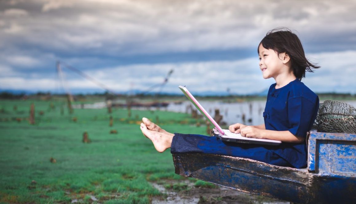 Asian children in local dress are using laptop for education and